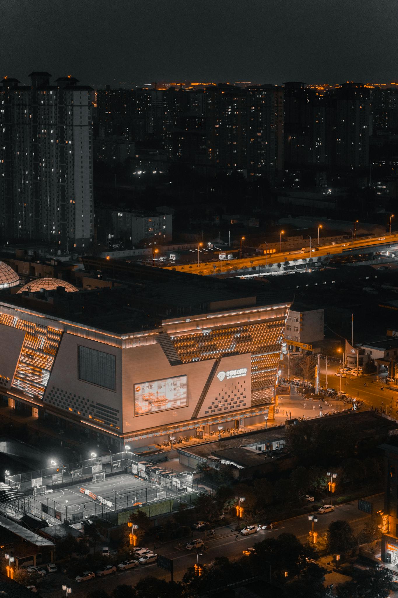 Aerial view of a brightly lit cityscape showcasing buildings and roads under the night sky.