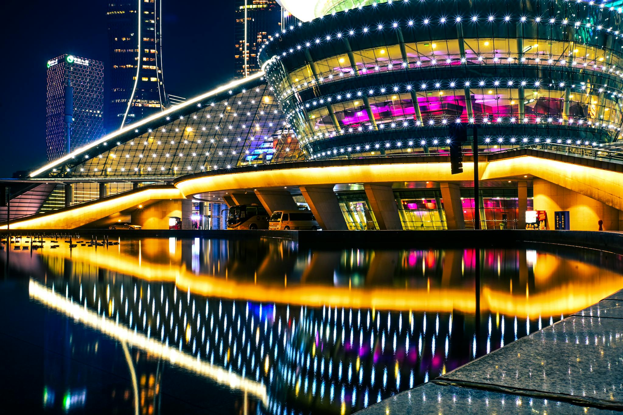 Vibrant night view of Hangzhou Grand Theatre with reflective lighting.
